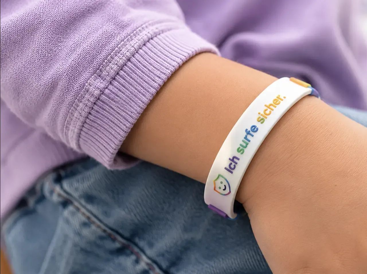 A child wearing a KidsProxy wristband that reads “Ich surfe sicher.”